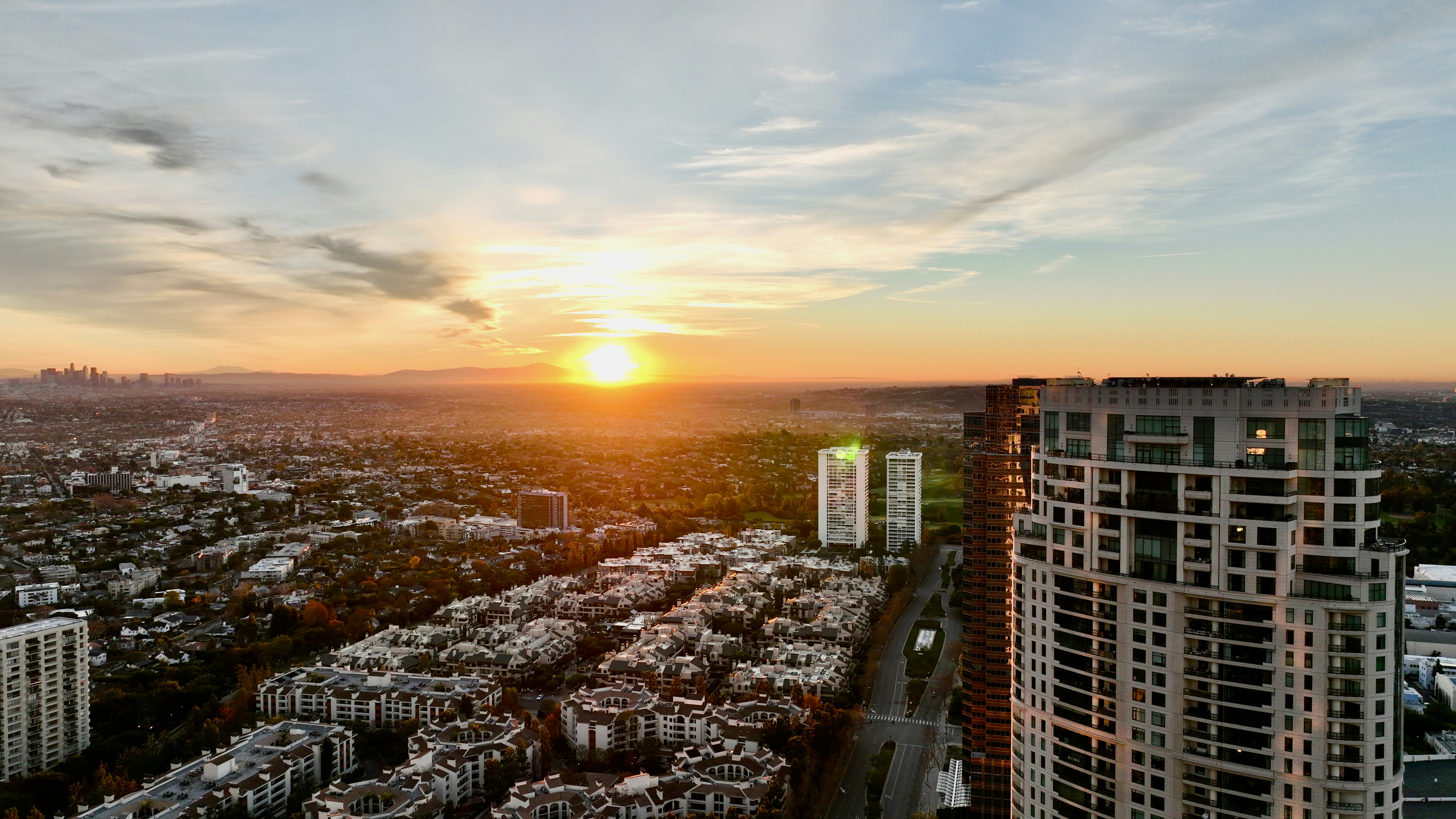 the sun is setting over a city with tall buildings