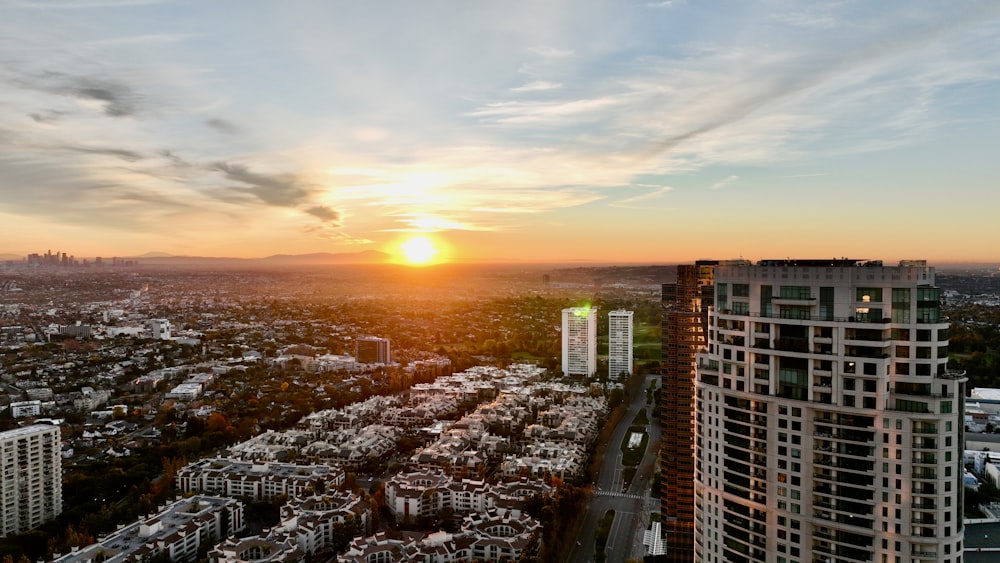 the sun is setting over a city with tall buildings