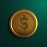 A gold coin with a dollar sign embossed on it set against a dark green background. The coin is circular with reflective surfaces, highlighting its metallic texture.