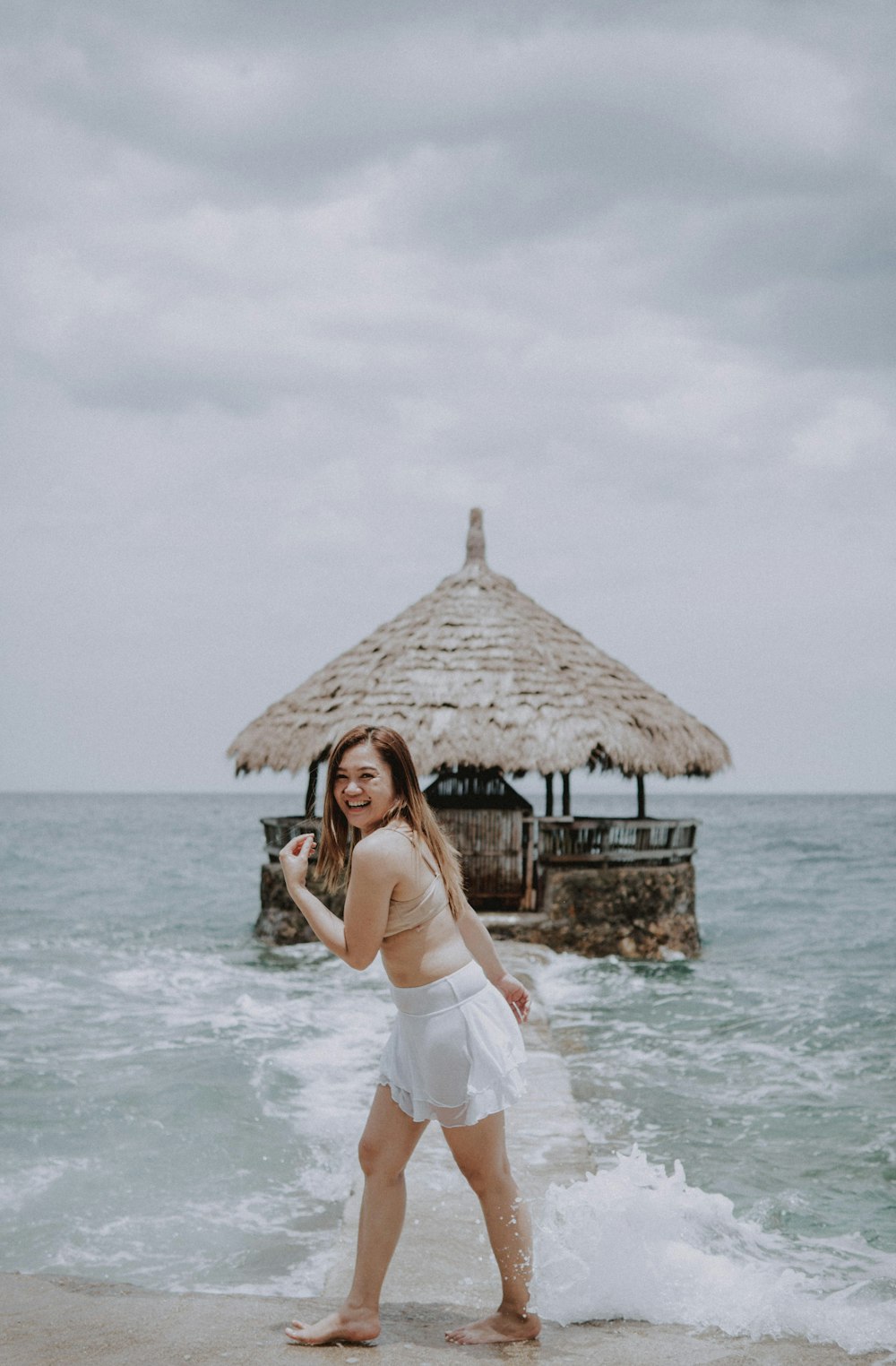 a woman standing on top of a sandy beach next to the ocean