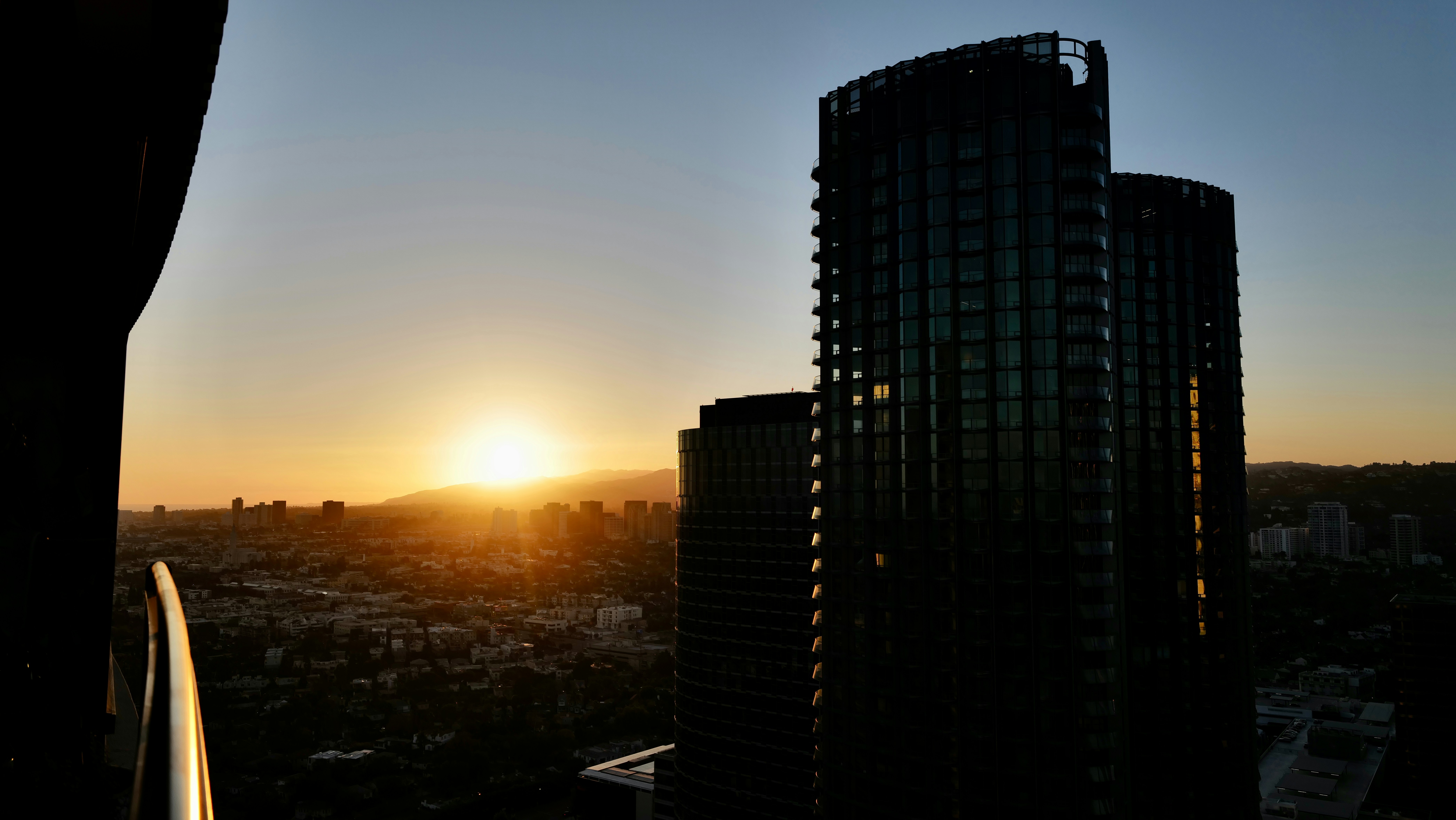the sun is setting over a city with tall buildings