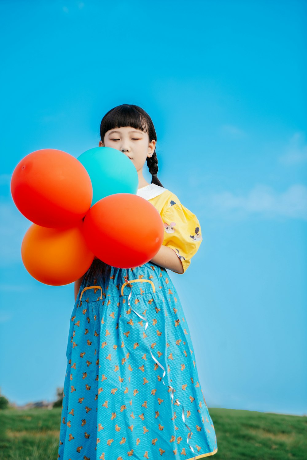 a little girl holding a bunch of balloons