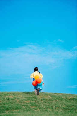A cheerful child holding colorful balloons at a lively outdoor festival.
