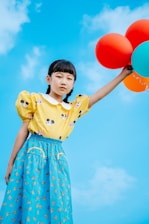 A joyful Bangladeshi child holding colorful balloons and toys.