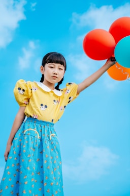 A cheerful child holding colorful balloons at a lively outdoor party.