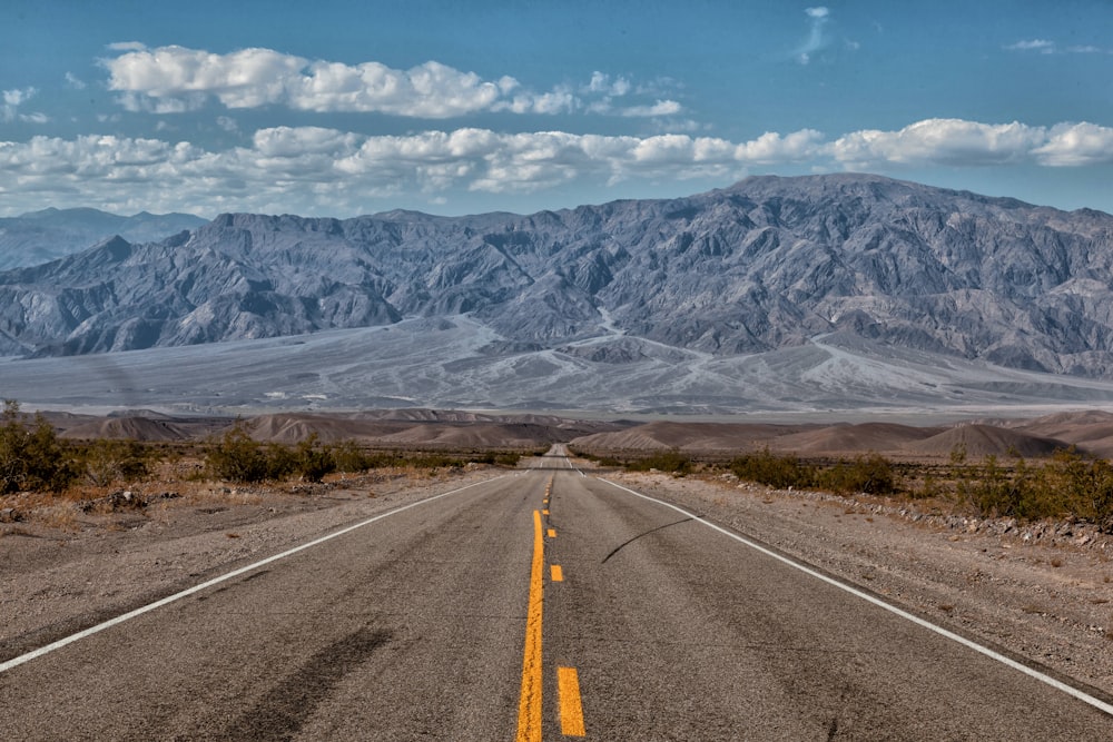 an empty road with mountains in the background