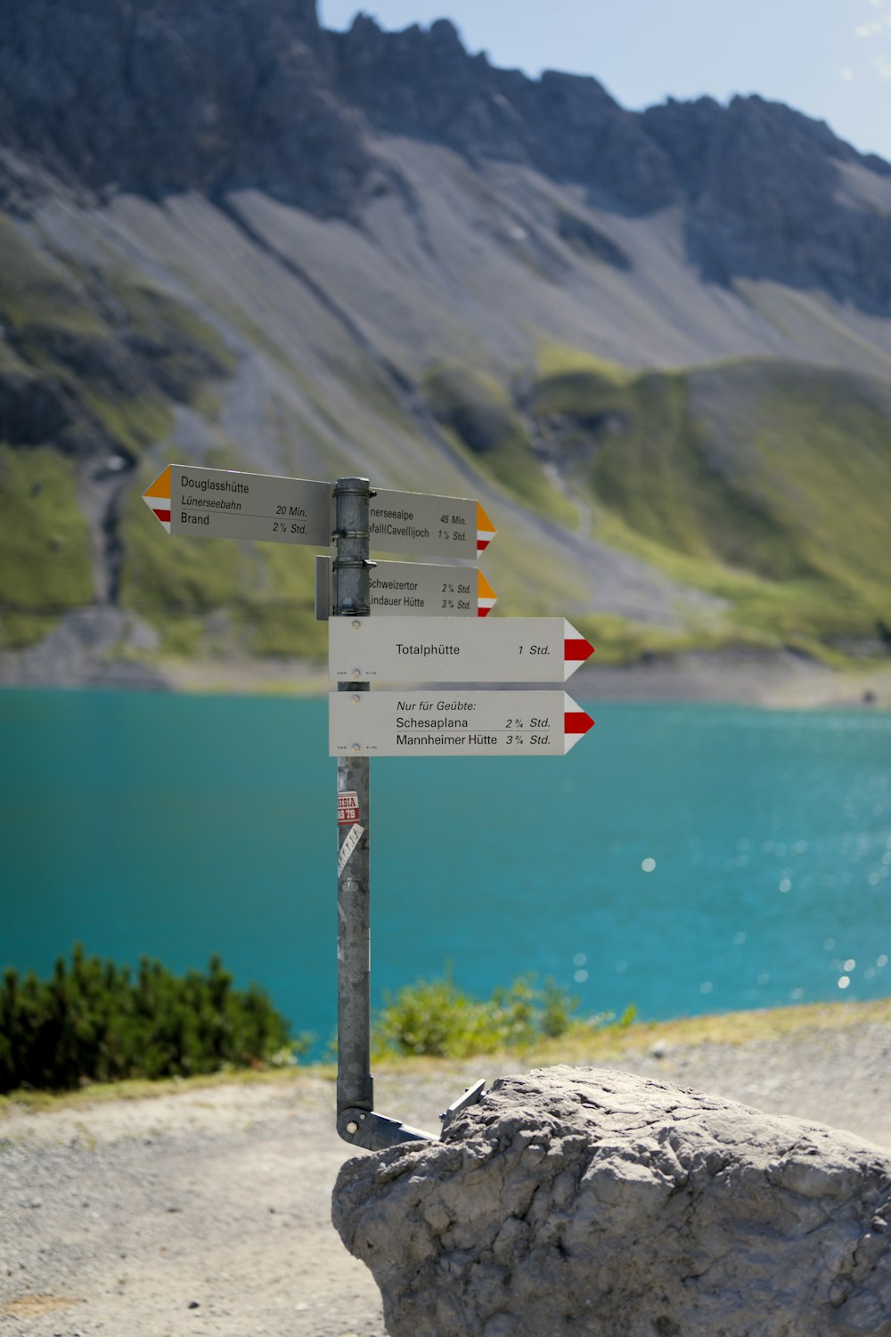 a sign on the side of a mountain with a lake in the background