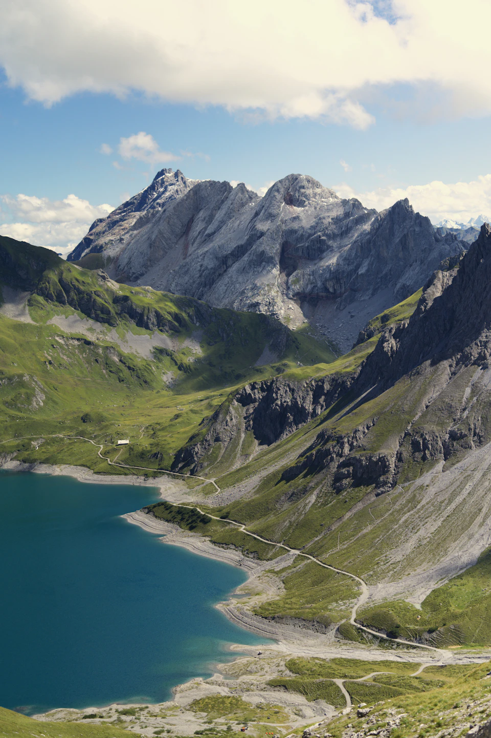 Serene mountainous landscape with lake at its base, surrounded by lush green mountains and trees