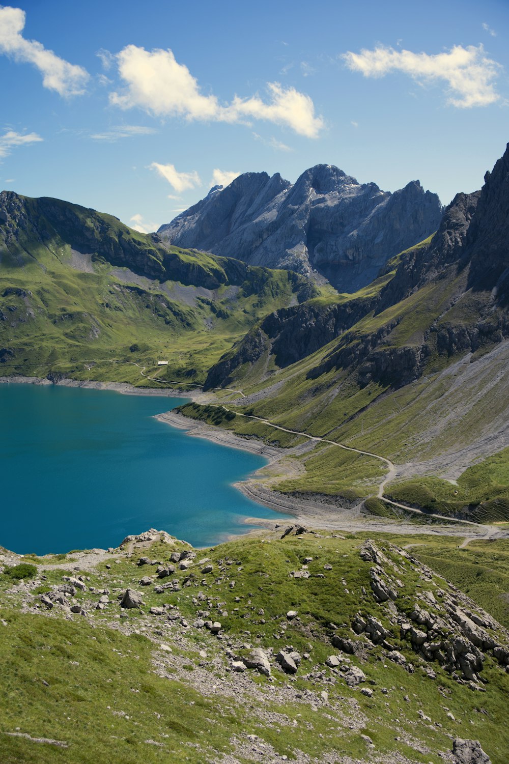 a blue lake surrounded by mountains under a blue sky