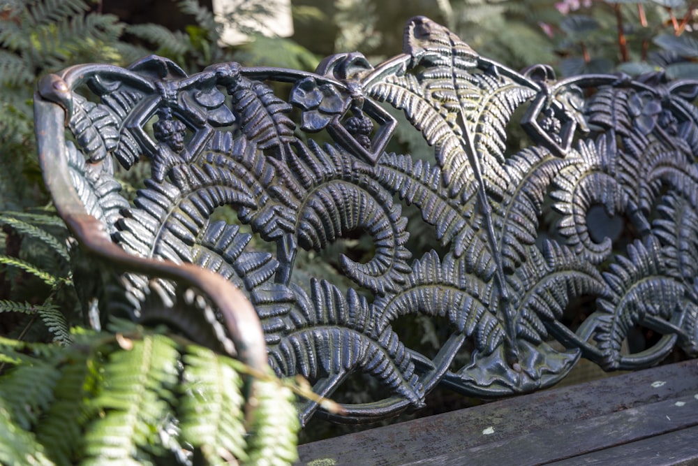 a close up of a bench with plants in the background