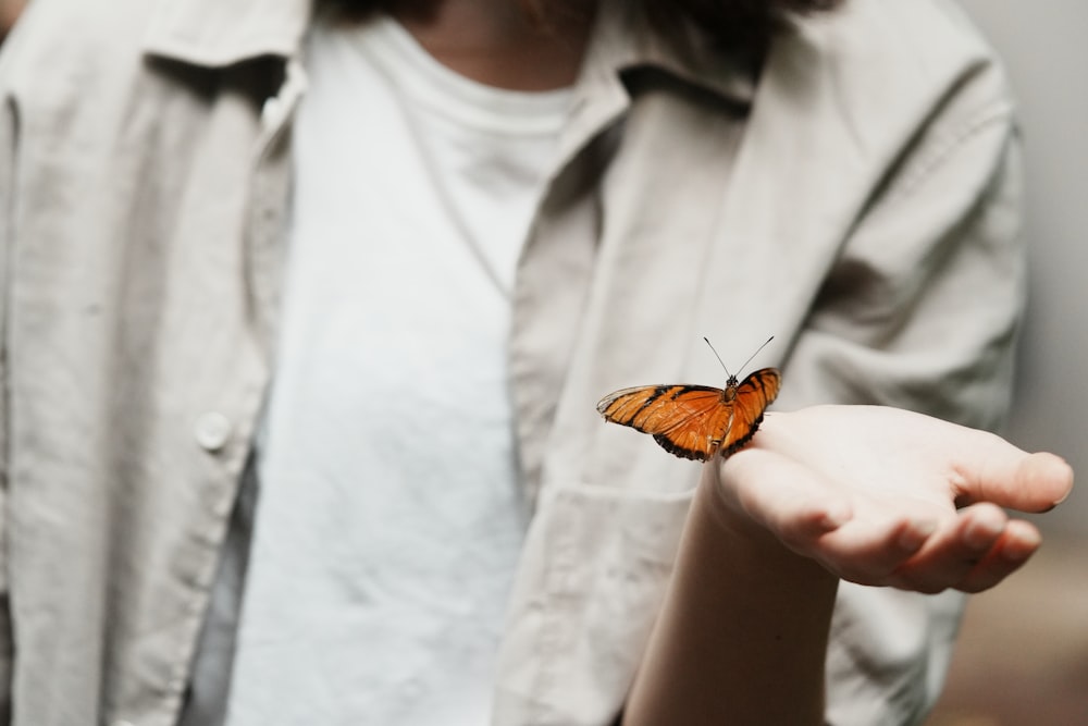 a close up of a person holding a butterfly