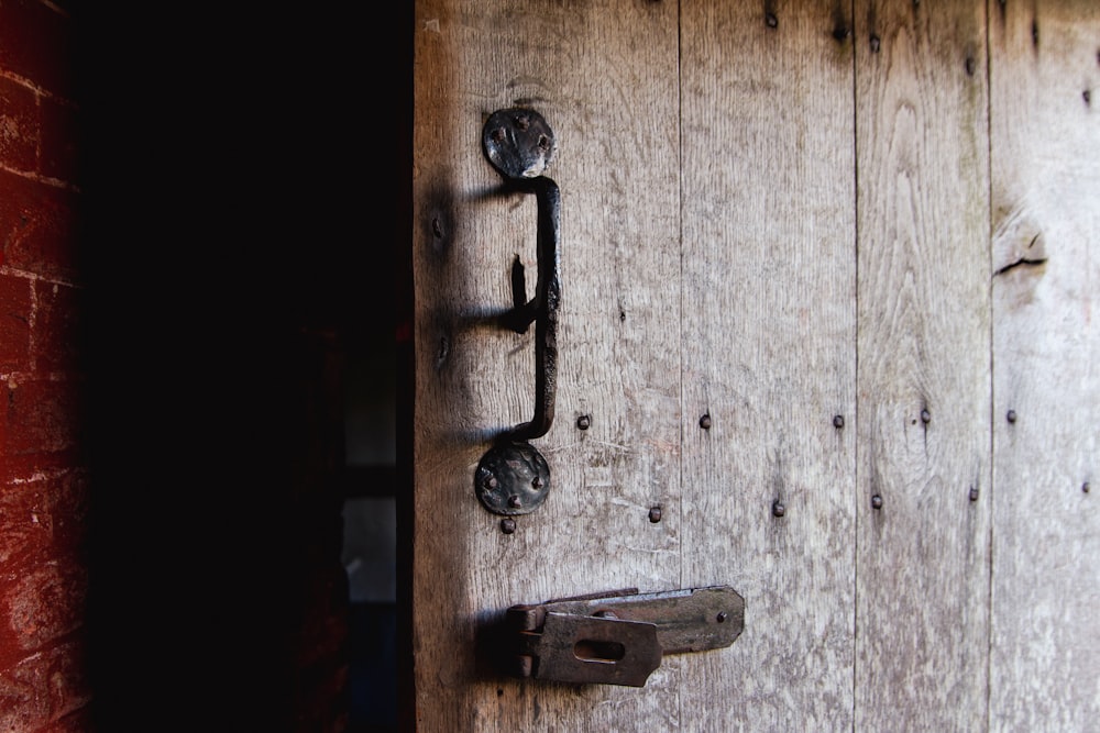 a door handle on a wooden door with a brick wall in the background