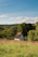 A cozy wooden cottage surrounded by lush greenery under a clear blue sky.