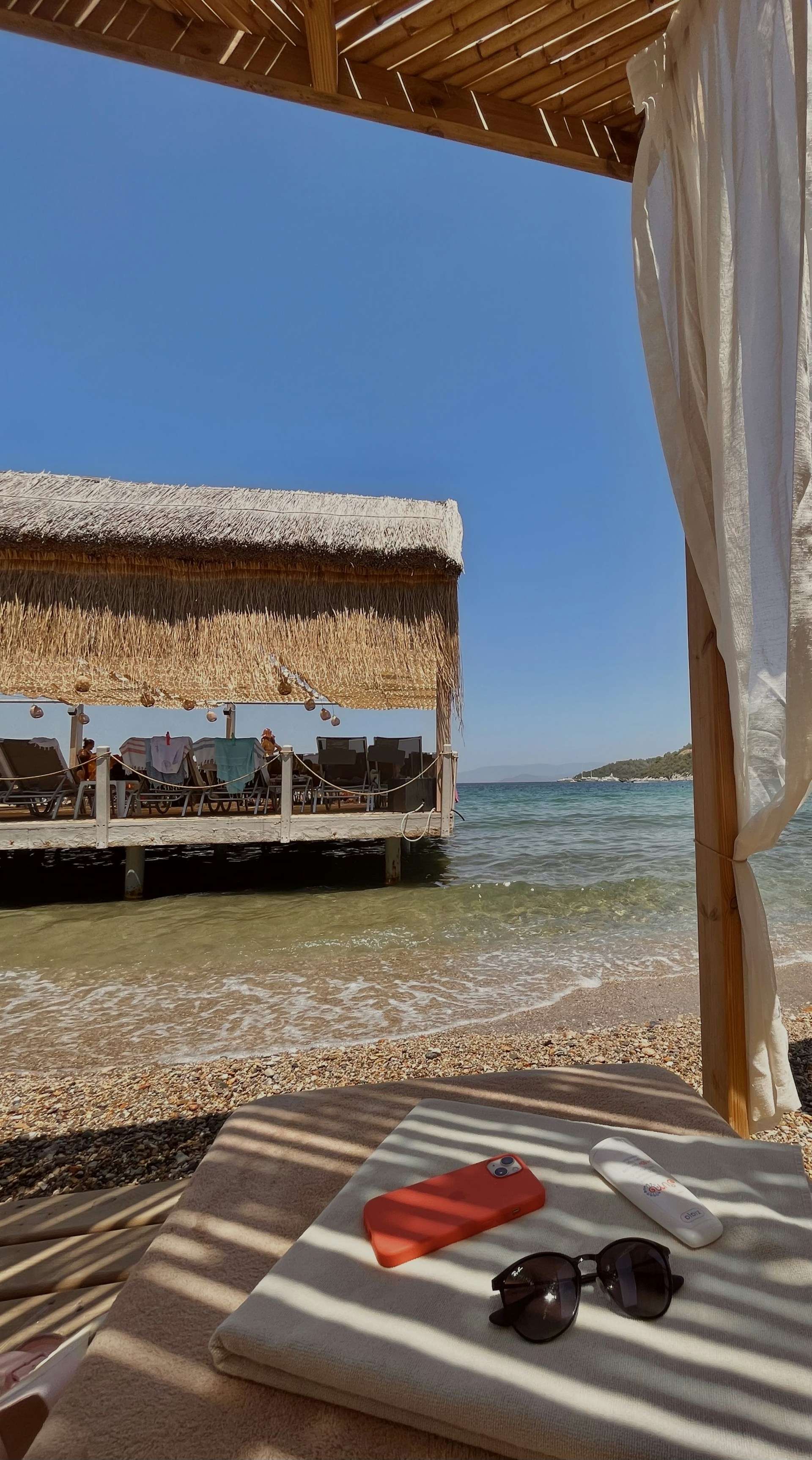 An inviting luxury cabana on the beach at The Sanctuary Antigua, featuring elegant furnishings, flowing white curtains, and the sparkling Caribbean Sea just steps away.