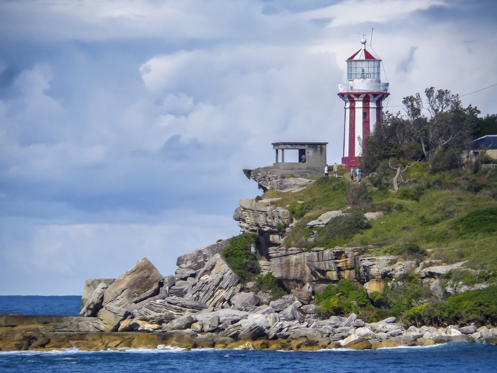 a red and white lighthouse sitting on top of a cliff