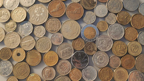 A display case filled with diverse coins from different historical periods.