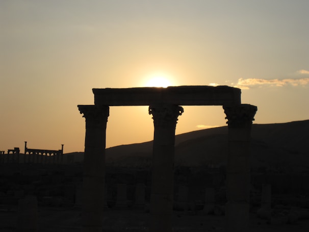 Golden hour light casting long shadows over ancient ruins in a Mediterranean village