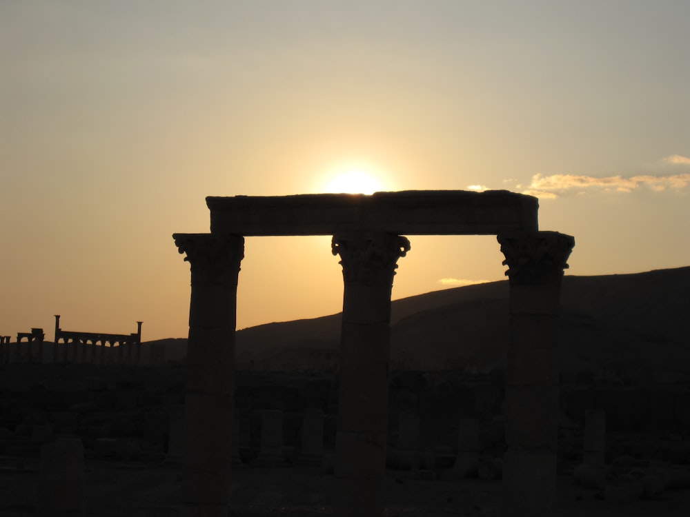 the sun is setting over the ruins of a roman city