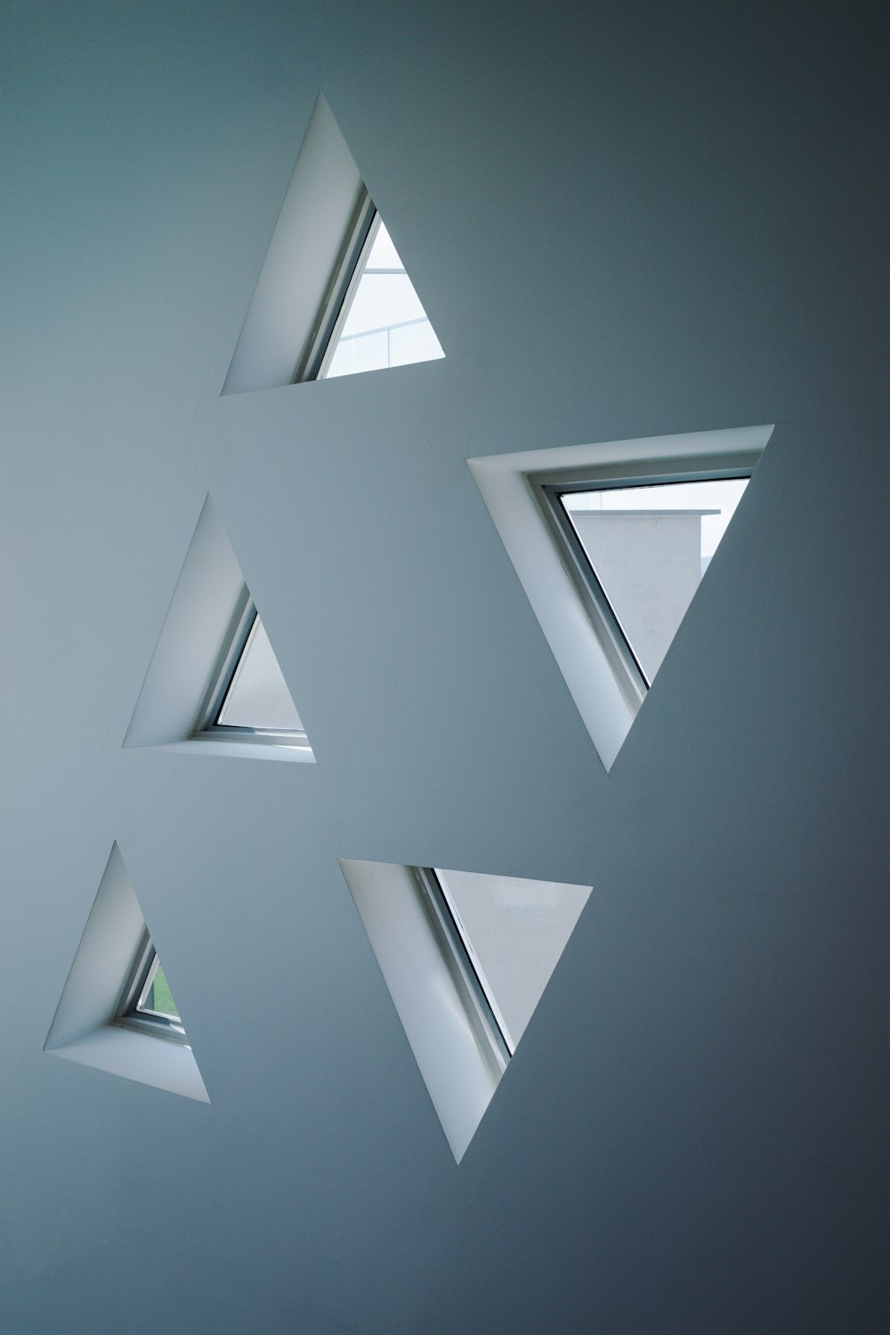 a group of triangular windows in a white room