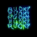 A series of glowing neon letters spelling out 'RUOK?' multiple times, arranged in a grid pattern against a black background. The neon letters vary in shades of blue and green, giving a vibrant and dynamic appearance.