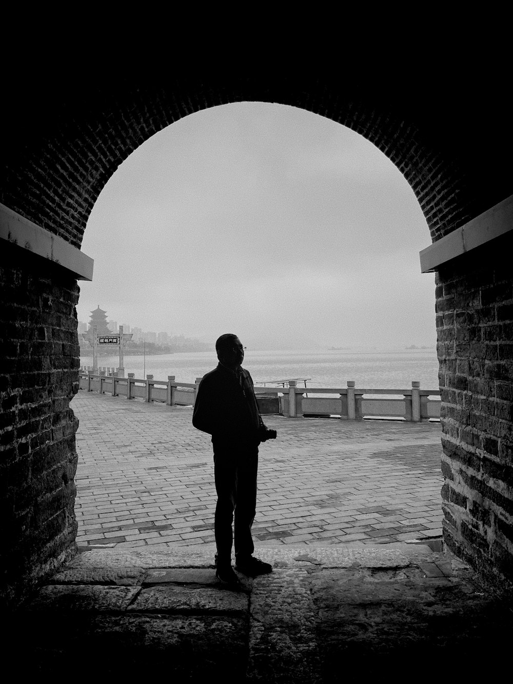 a man standing in a tunnel looking out at the ocean