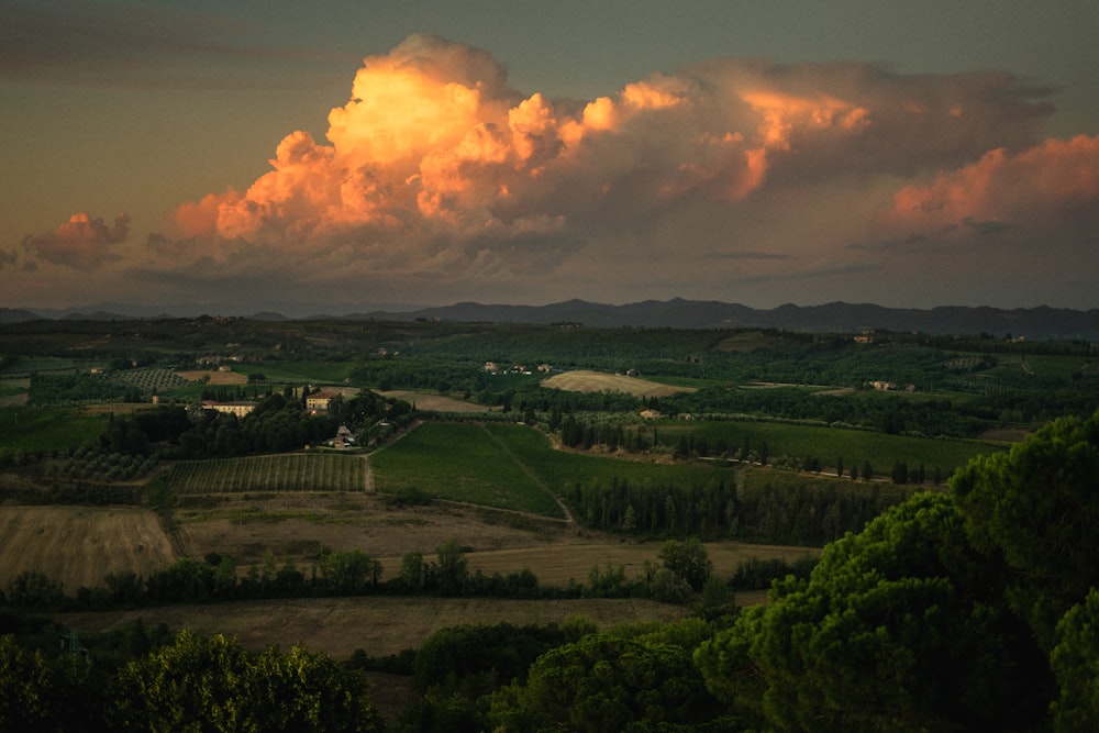 a large cloud hangs over a rural landscape