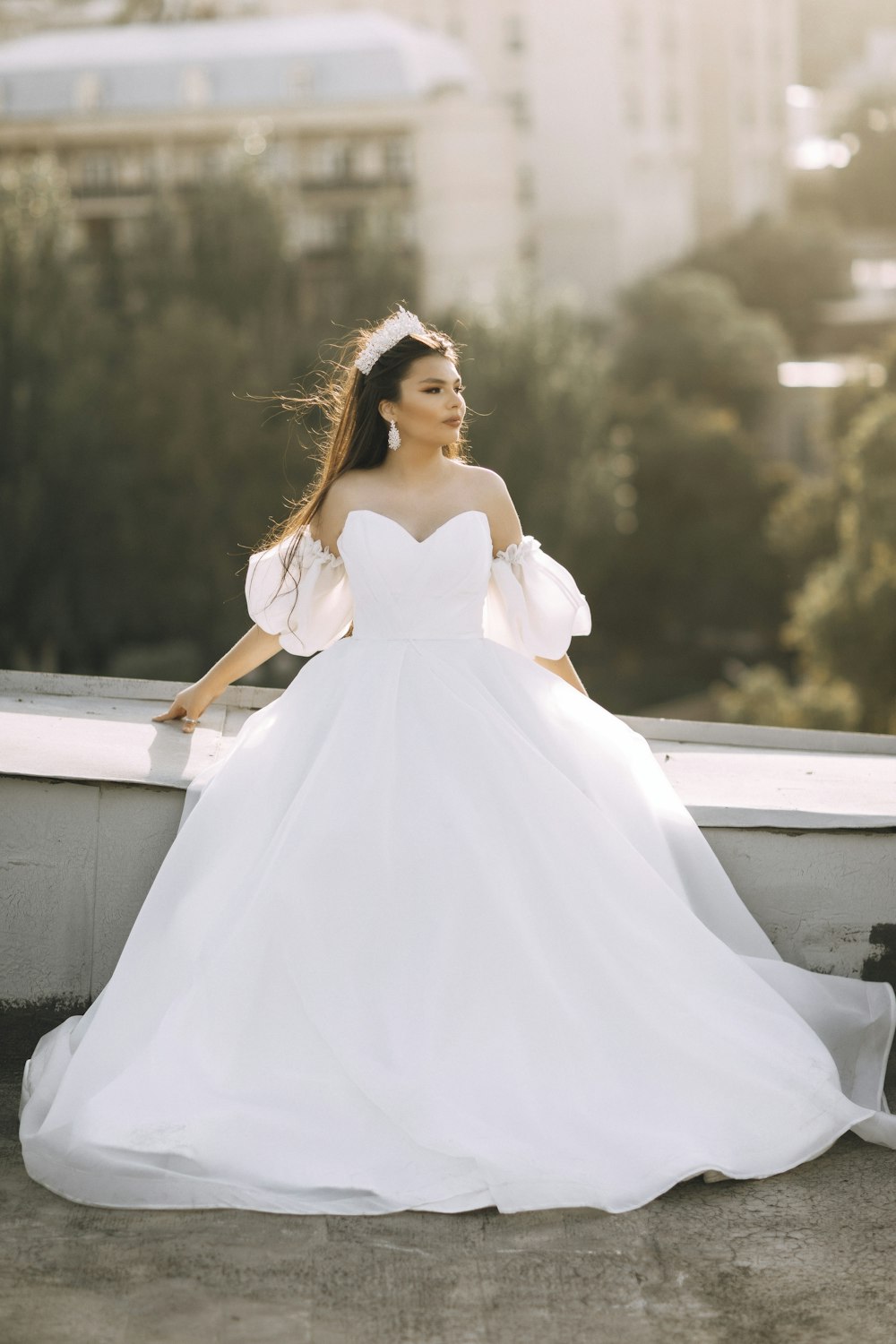 a woman in a white wedding dress standing on a ledge