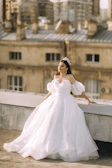 Elegant evening gown flowing gracefully on a sunlit rooftop terrace.