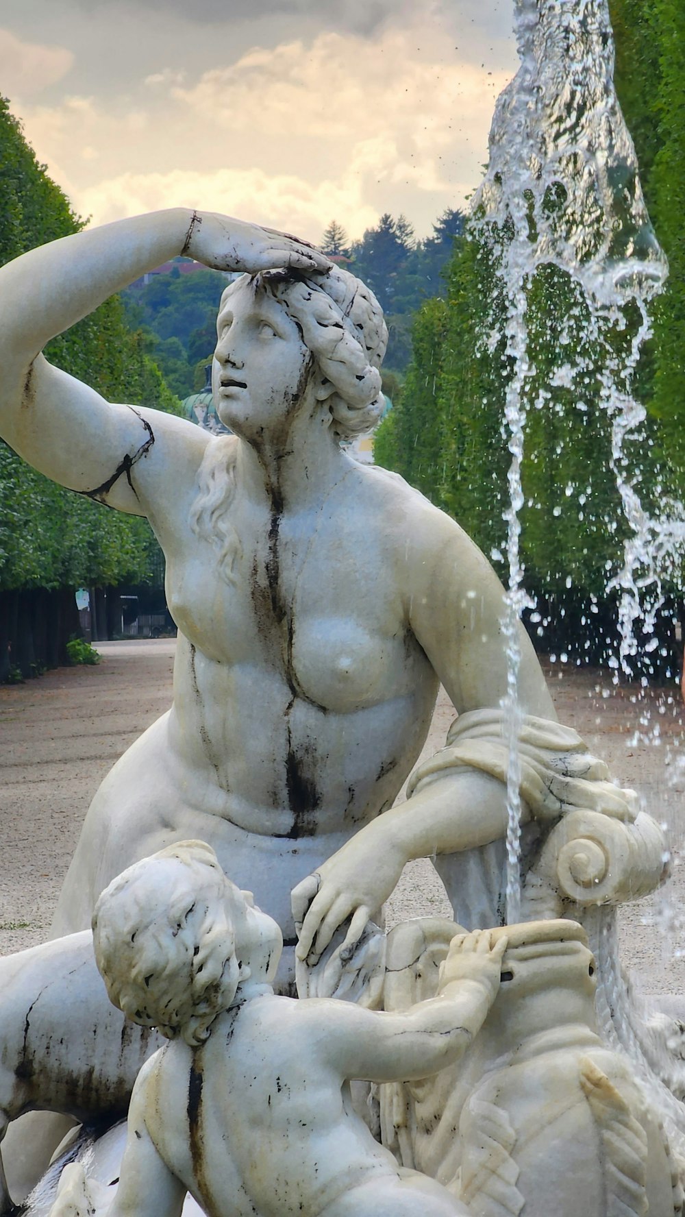 a statue of a man holding a woman's head in front of a fountain