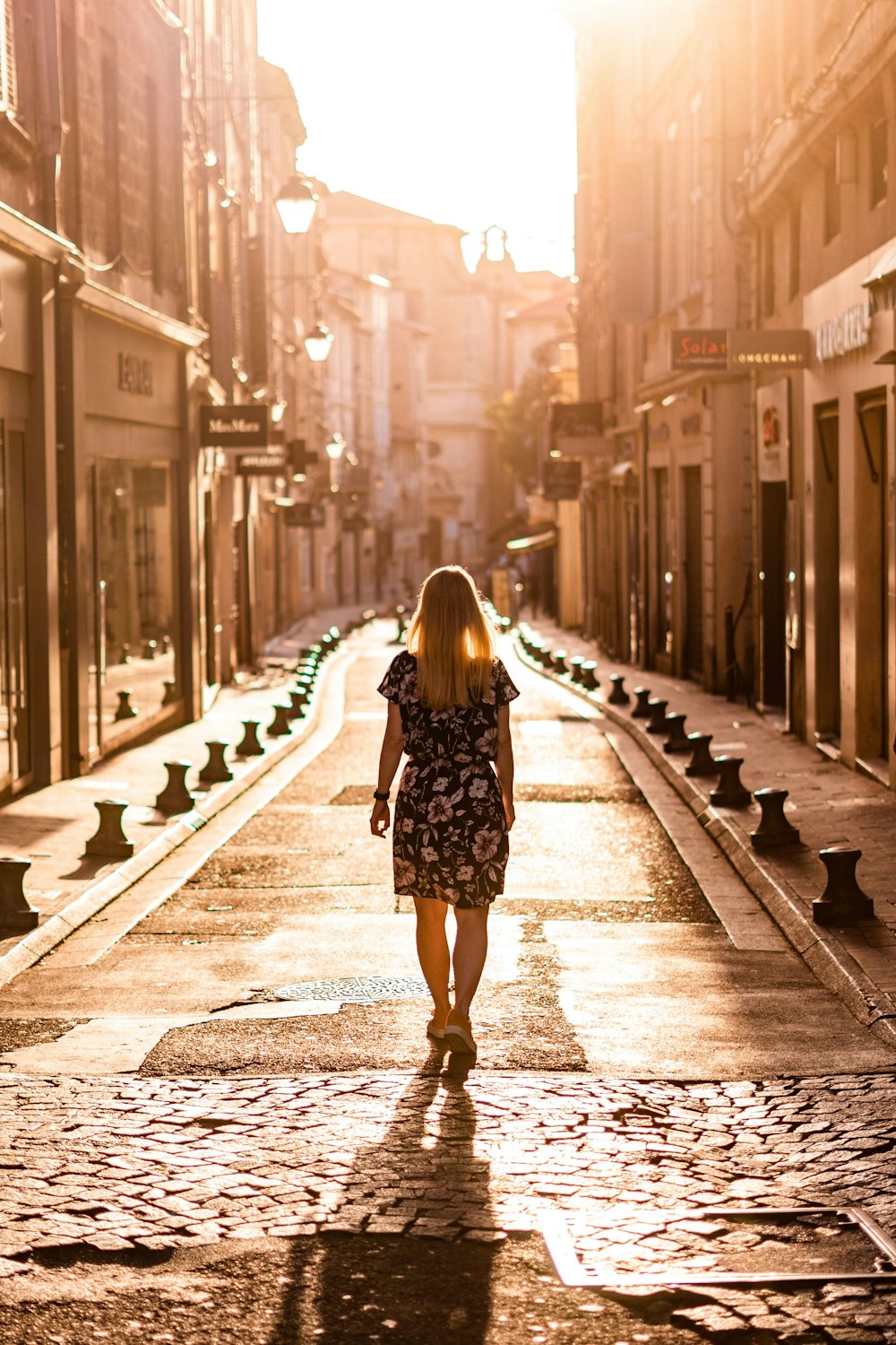 a woman walking down a street next to tall buildings