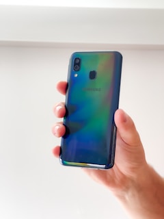 A hand holding a shiny Samsung phone showcasing the screen’s vibrant colors