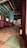 A traditional wooden interior with colorful ceiling beams, featuring intricate patterns and vibrant colors. The room contains several cushions on a polished wooden floor, suggesting a space for meditation or relaxation. Soft lighting filters through paper-covered windows, creating a serene and peaceful atmosphere.