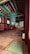 A traditional wooden interior with colorful ceiling beams, featuring intricate patterns and vibrant colors. The room contains several cushions on a polished wooden floor, suggesting a space for meditation or relaxation. Soft lighting filters through paper-covered windows, creating a serene and peaceful atmosphere.