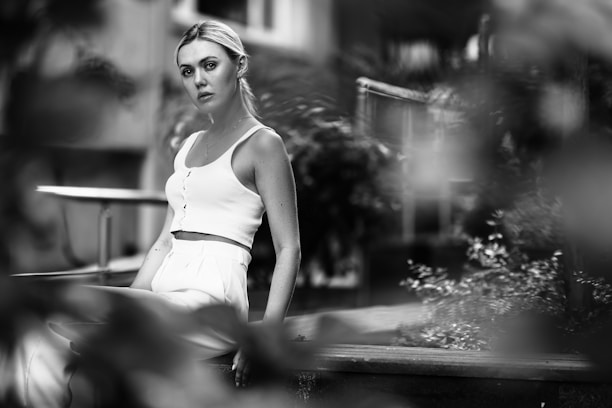 A serene woman sitting outdoors, reflecting thoughtfully with soft natural light.