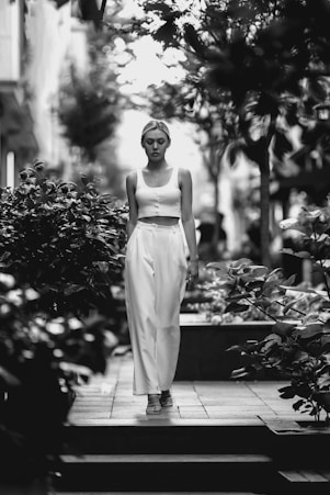 A serene image of a woman walking confidently along a sunlit path surrounded by soft terracotta tones.