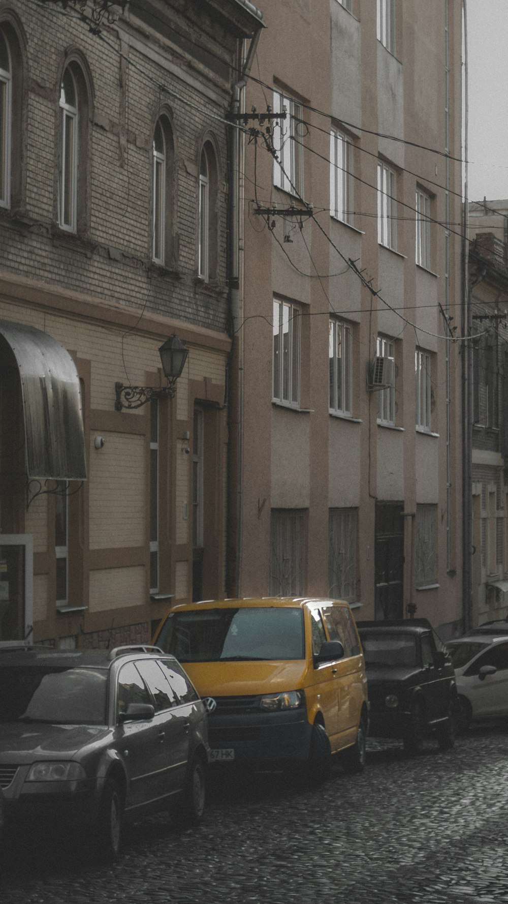a yellow car is parked on a cobblestone street