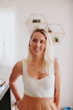 A young beautician warmly smiling in a minimalist, sunlit studio, radiating calm and professionalism.