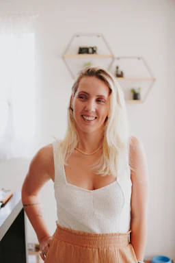 A professional blonde female dentist smiling warmly while consulting a patient in a bright, clean clinic setting