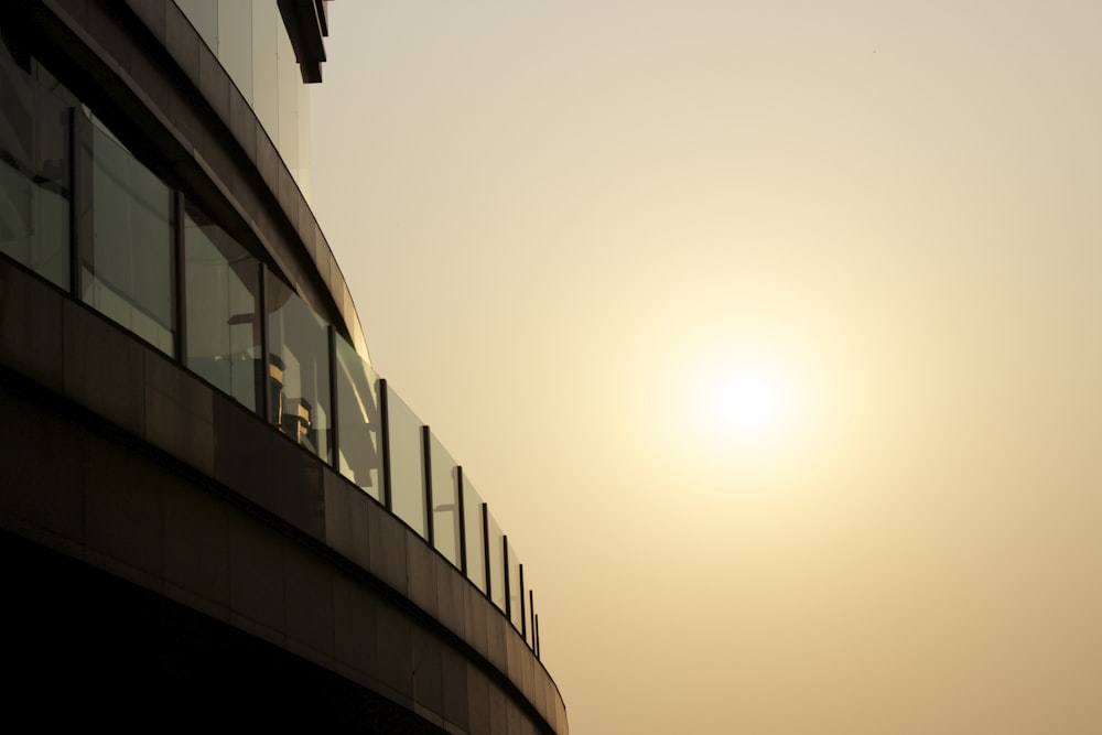 the sun is setting behind a building with a balcony