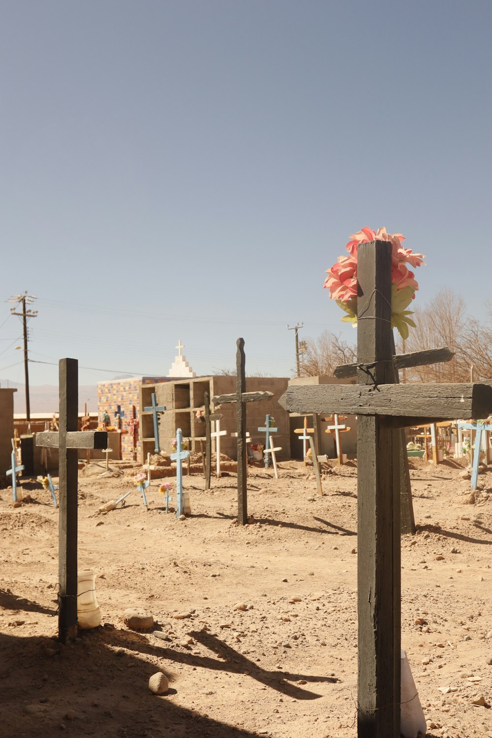 a wooden cross sitting in the middle of a dirt field