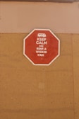 A red octagonal sign mounted on a tan-colored wall with the text 'KEEP CALM AND RENT A WICKED VAN' in white letters along with a white icon of a van at the top.