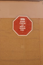 A red octagonal sign mounted on a tan-colored wall with the text 'KEEP CALM AND RENT A WICKED VAN' in white letters along with a white icon of a van at the top.