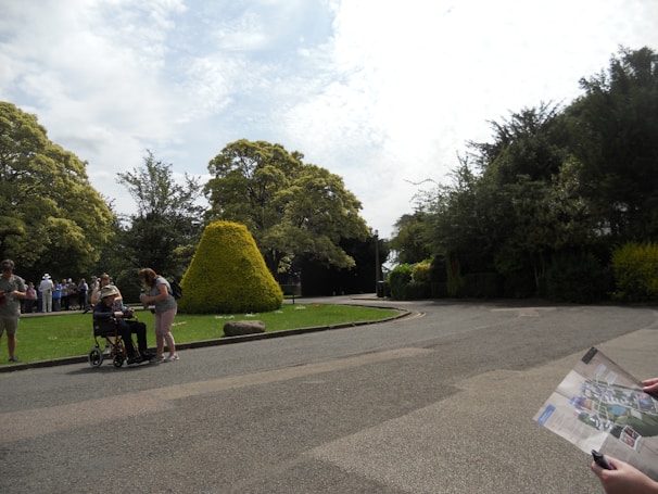 A personal assistant helping a person with a wheelchair navigate a peaceful park pathway.