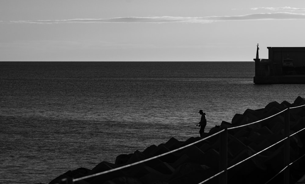 a black and white photo of a person walking on a pier