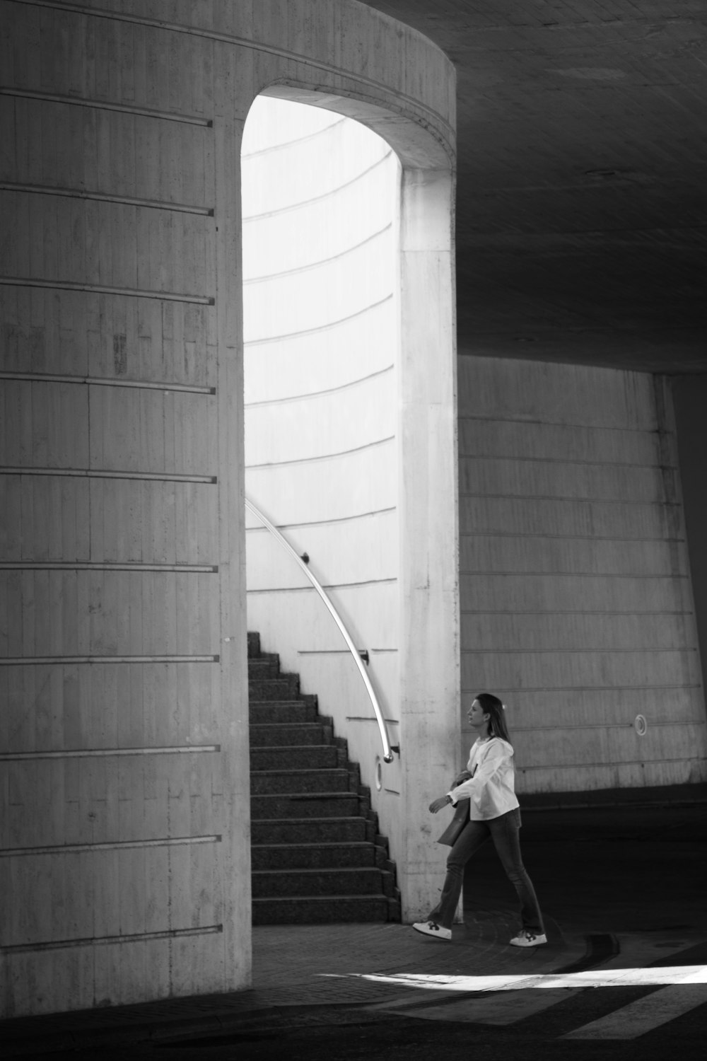 a woman walking down a street next to a tall building