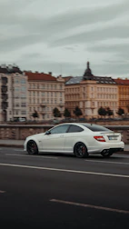 A professional driver carefully delivering a premium sedan on a scenic European road.