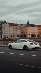 A professional driver carefully delivering a premium sedan on a scenic European road.