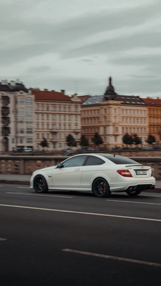 A professional driver carefully delivering a premium sedan on a scenic European road.