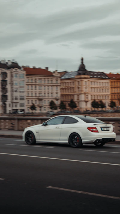 A professional driver carefully delivering a premium sedan on a scenic European road.