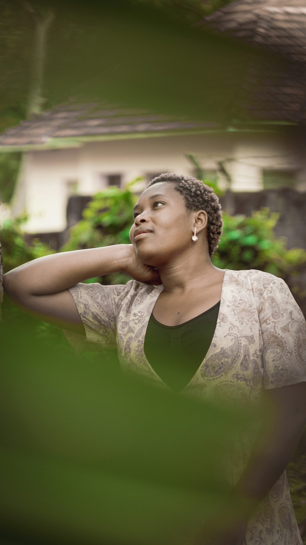 a woman leaning against a tree with a house in the background